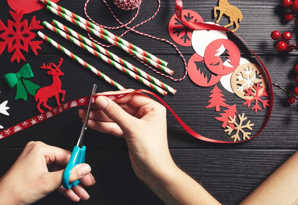 DIY Christmas Tree Ornaments - person cutting ribbon during crafting