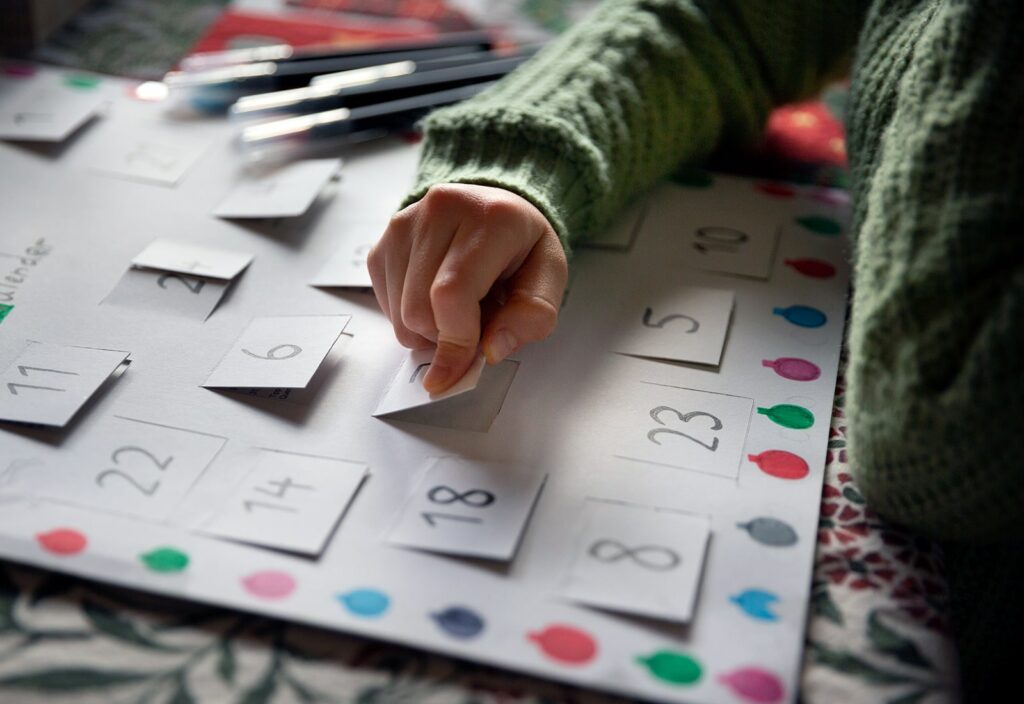 kids advent calendar feature - child opening a day on a paper advent calendar